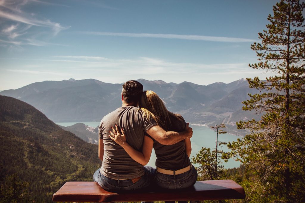 pexels photo 1417255 1417255 Couple sitting on bench embracing scenic mountain view, embodying romantic nature escape.