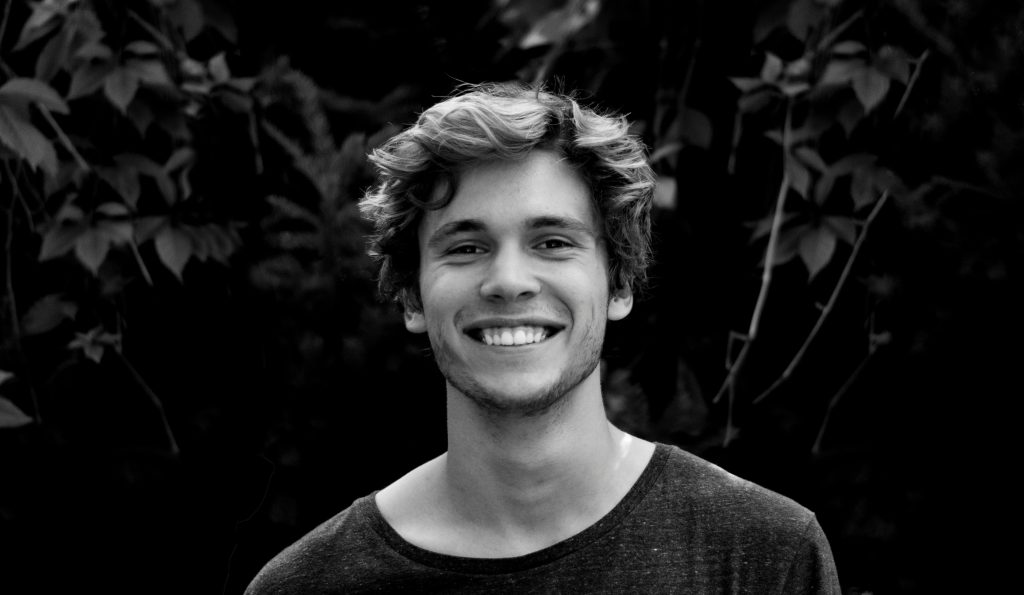 pexels photo 91227 91227 A black and white portrait of a young man smiling outdoors with natural background.